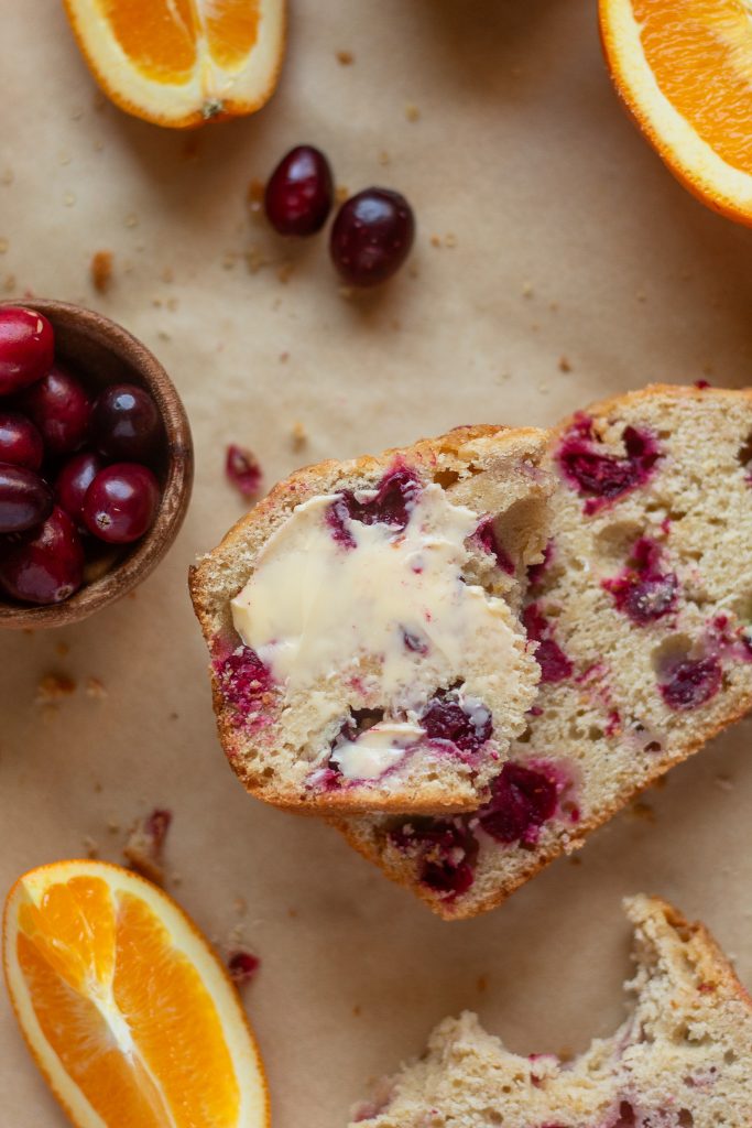 overhead shot of sliced cranberry orange bread with butter on bread
