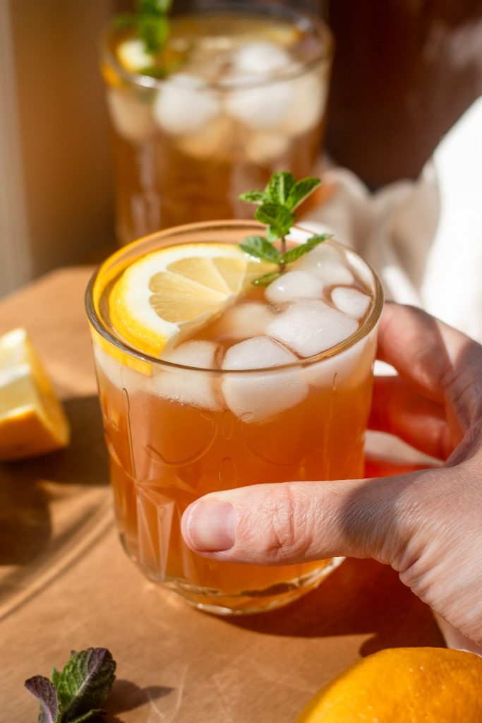hand picking up garnished individual glass of arnold palmer drink